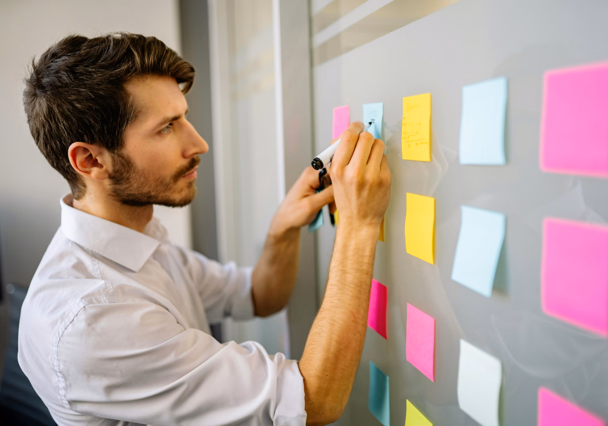Someone arranging sticky notes on a glass wall